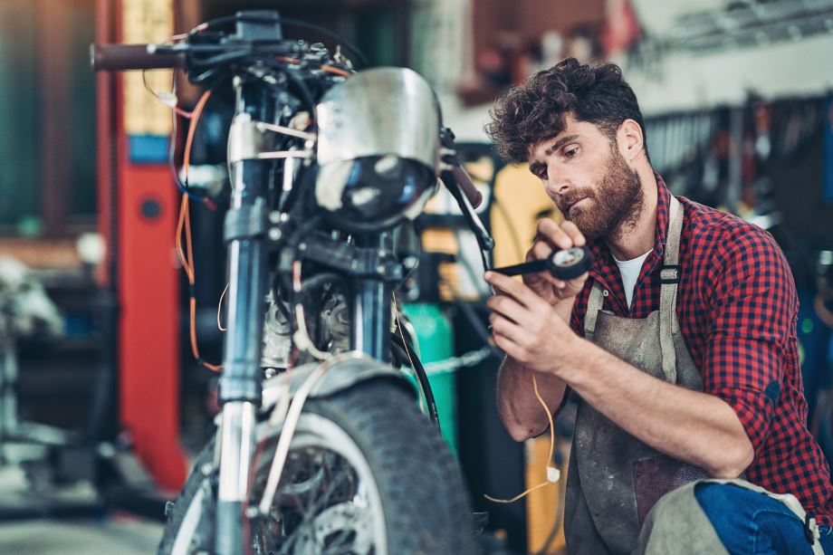 man maintaining his motorcycle before putting it in long-term motorcycle storage