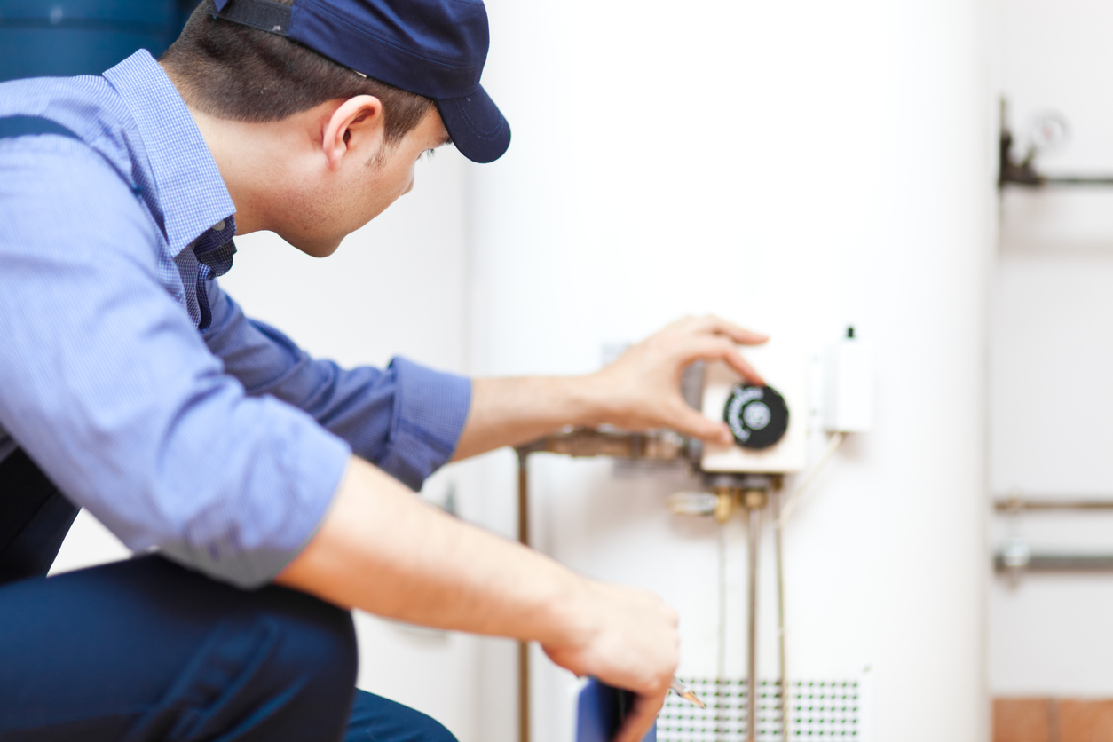 A technician draining and inspecting a hot water heater before winter vacancy