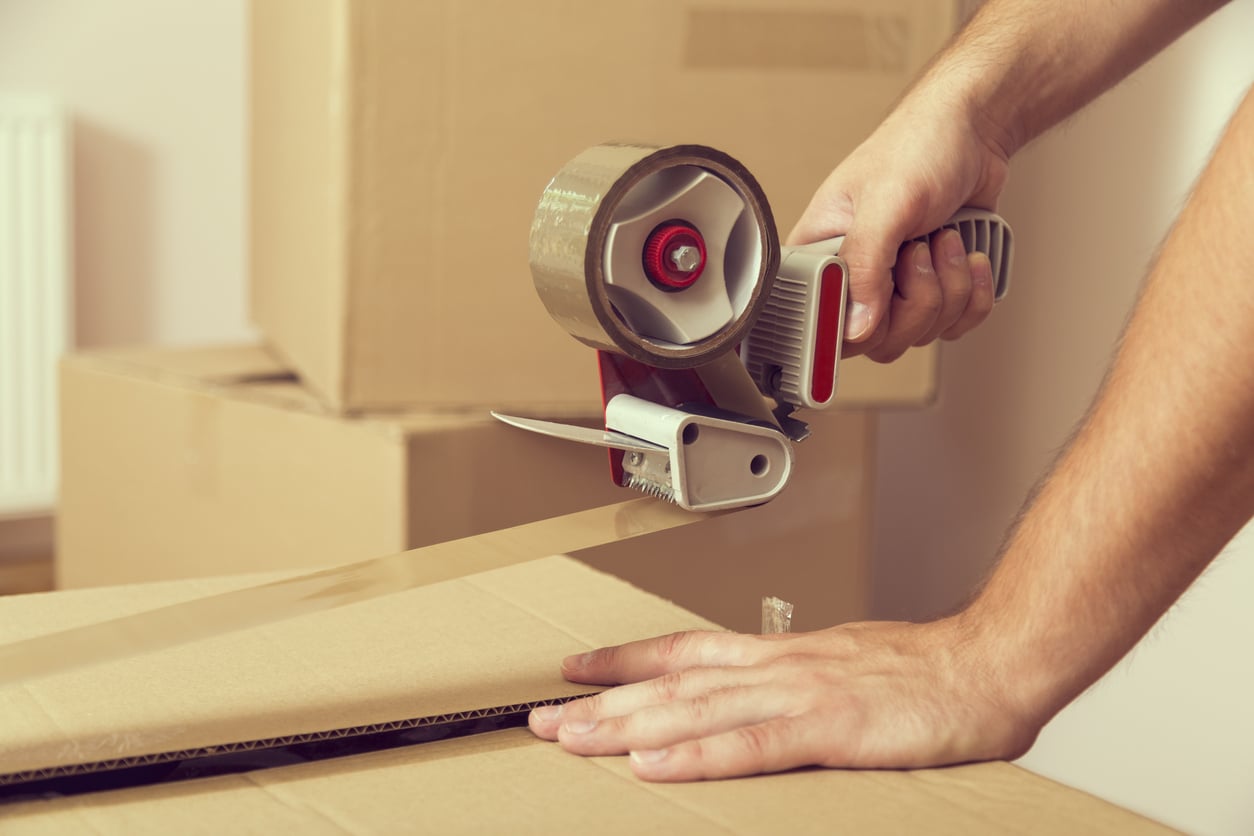 close-up of someone using a tape dispenser to seal a moving box