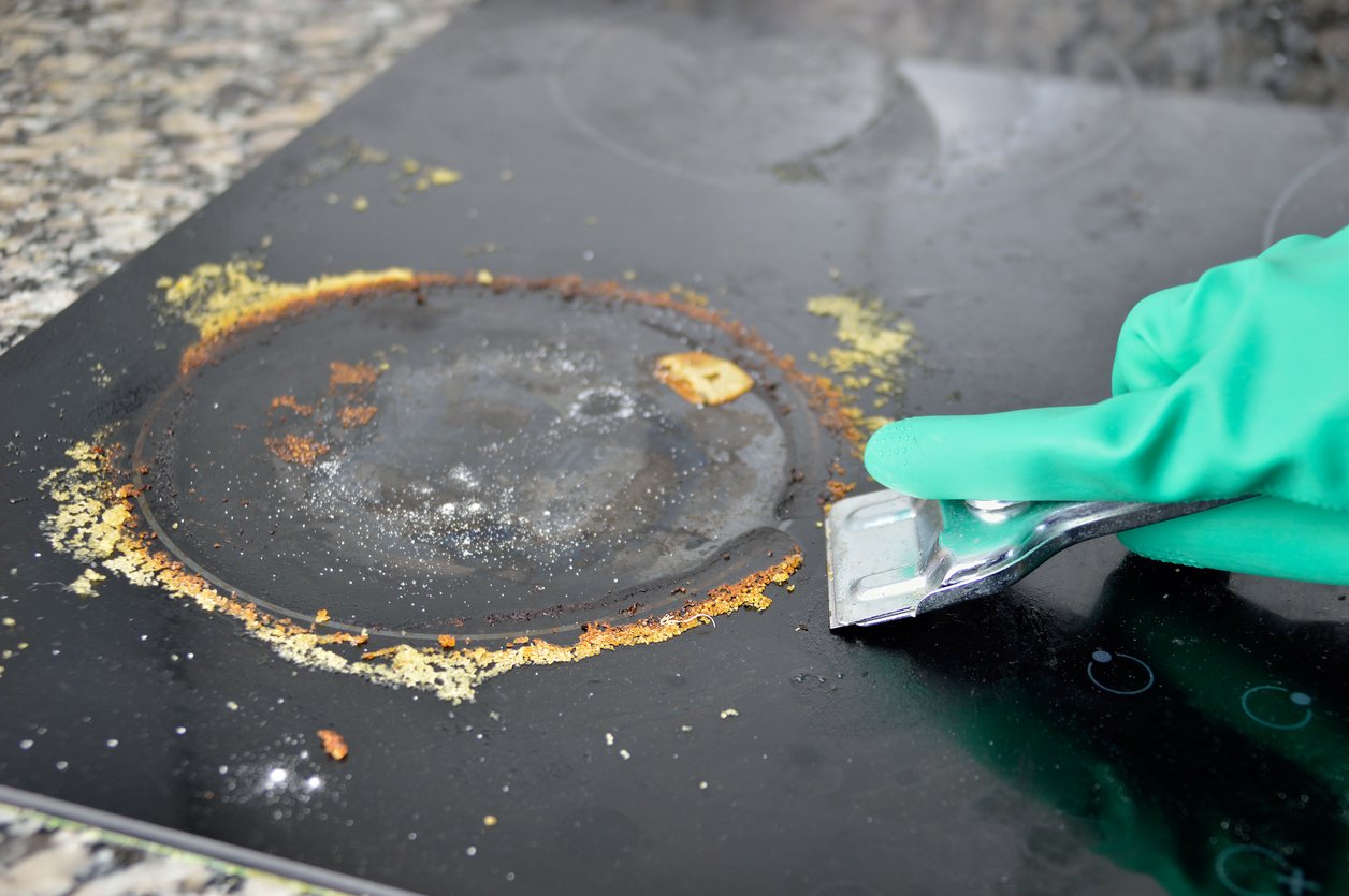 Hand holding a razor scraper and removing stuck stains